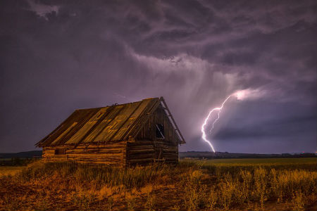 barn under dark clouds with a lightning bolt beside it