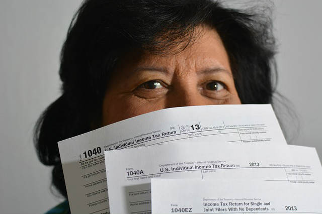woman hiding behind income tax forms