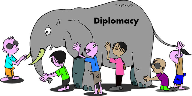 blindfolded boys feel around on different parts of an elephant which is labeled with the word "diplomacy"